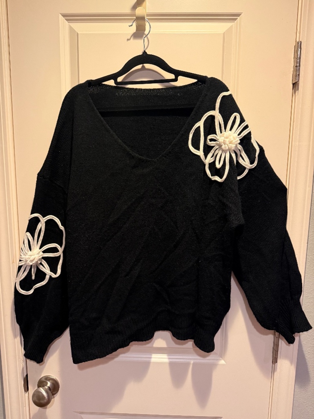 Black v neck sweater with white floral embellishment
